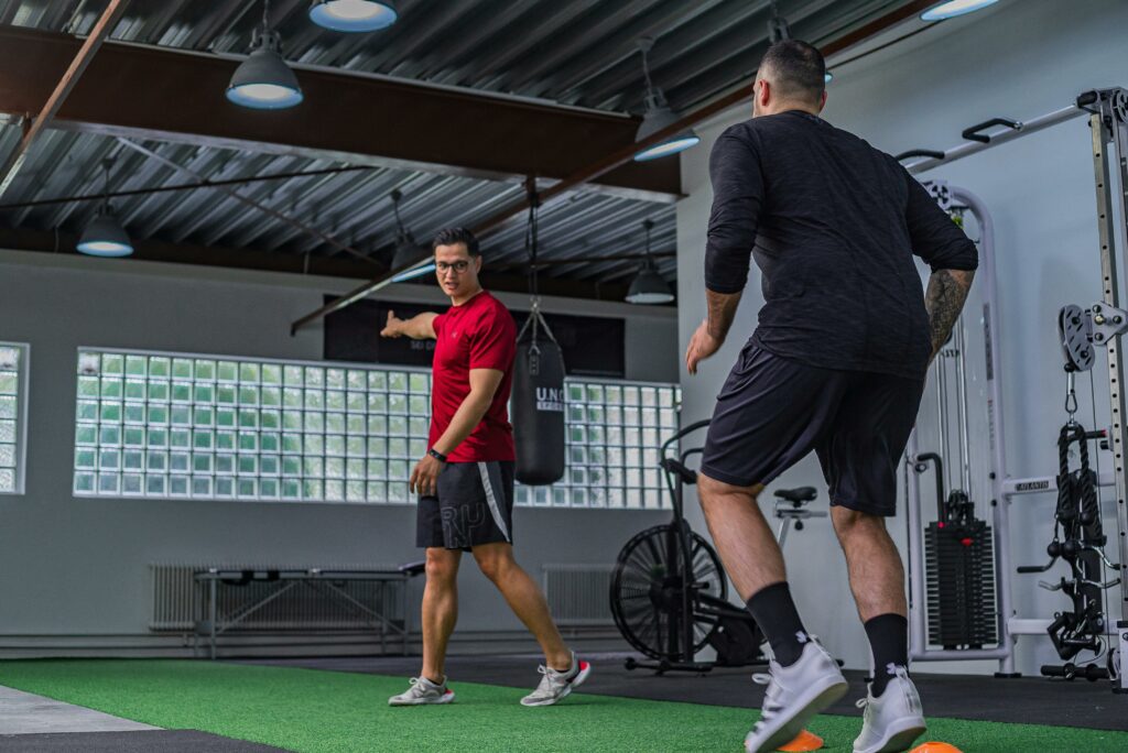 Activités Two men engaged in a dynamic workout with a personal trainer guiding a fitness session.